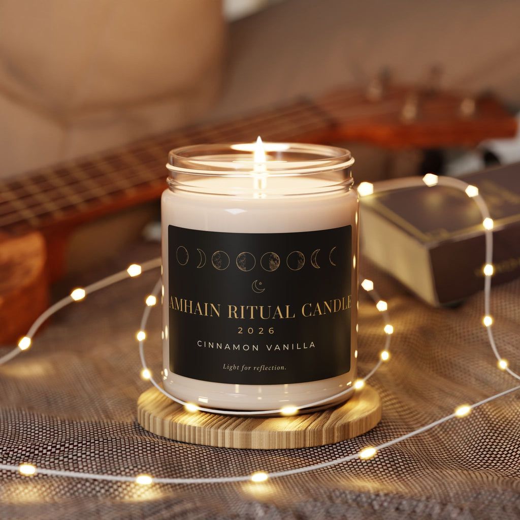 Lit Cinnamon Vanilla Samhain Ritual Candle on a wooden coaster with warm string lights